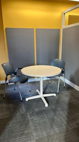 A table with two chairs in a partioned corner of the Digital Lab