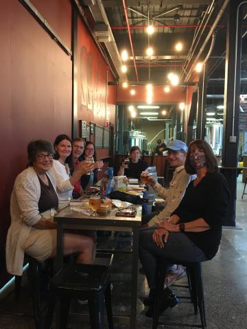 Book group participants sitting around the table at Stubborn Beauty Brewing. 