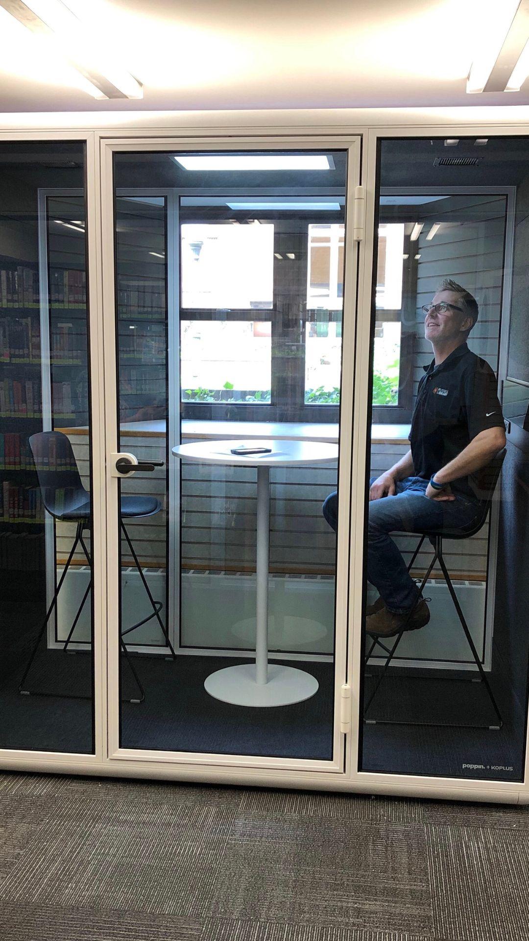 The Pod, an enclosed sound-proof booth with two chairs and a table.