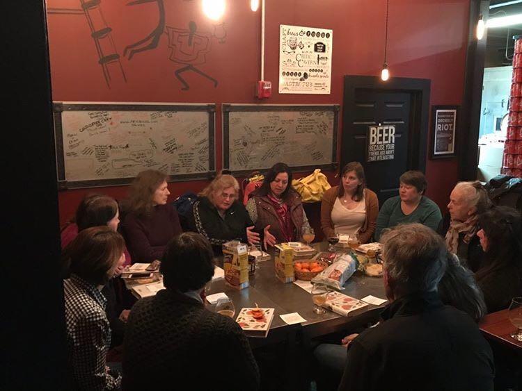 Book discussion participants sitting around a table a Stubborn Beauty Brewing.